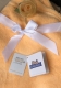 Flauschige orange Babydecke mit weißer Satinschleife und zarter, hellgelber Stoffrose. Zwei Anhänger liegen auf der Decke: Oeko-Tex Standard 100 Zertifikat und KiddiBaby-Label. Sie zeigen Sicherheit und Komfort.